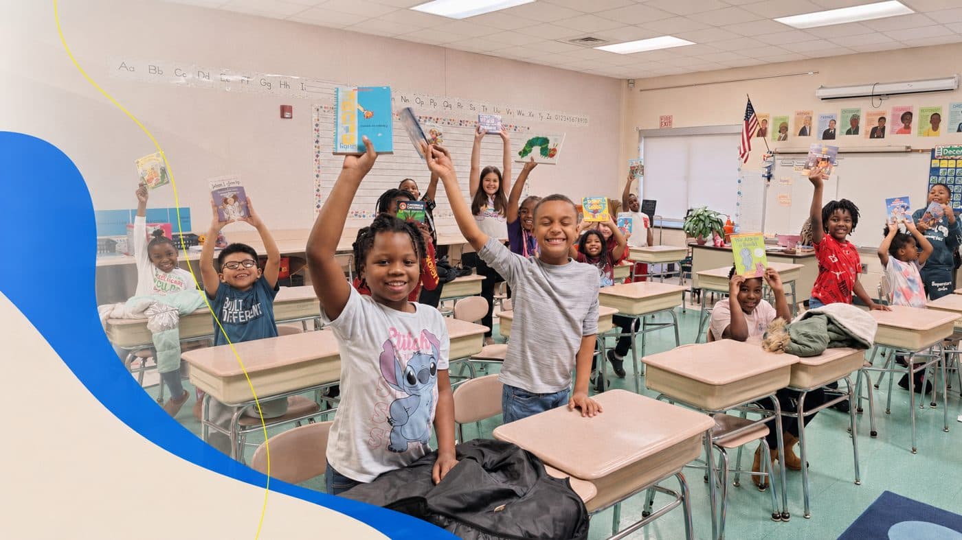 A classroom of smiling students holding up their new books